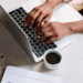 fresh blog content coming - hands of a black woman typing on an apple laptop at a table