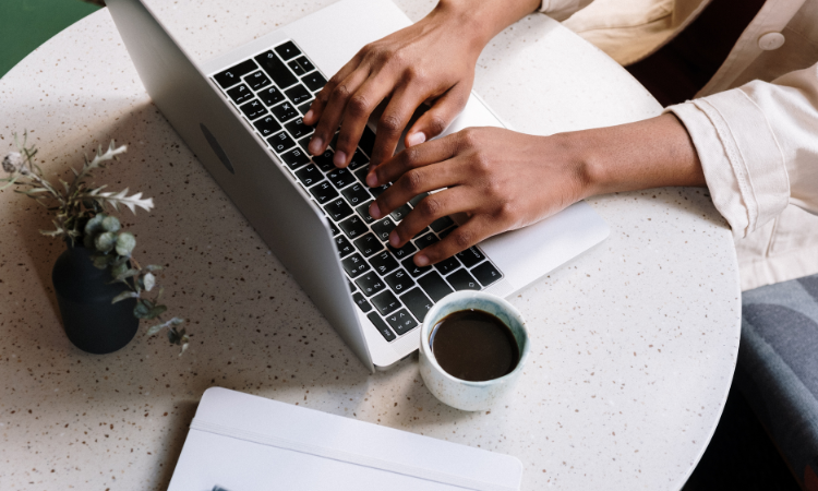 fresh blog content coming - hands of a black woman typing on an apple laptop at a table