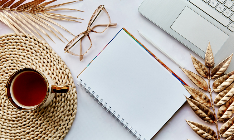 Overhead shot of a notebook, laptop, and a cup of tea